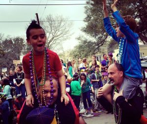 Nephew Jack sports a celebration mohawk and dangles beads in his father's face.  All part of the fun.  