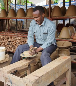 Surrounded by drying water filters, Mesiaki demonstrates his foot powered pottery wheel. 